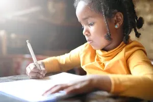 A young girl sits at a desk working on schoolwork